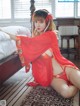 A woman in a red kimono sitting on a bed.