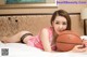 A woman laying on a bed holding a basketball.