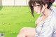 Anime girl sitting on the grass in a white shirt.