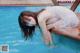 A woman in a white dress is sitting in a pool.