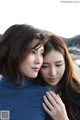 A couple of women standing next to each other on a beach.