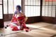 A woman in a red kimono sitting on the floor.