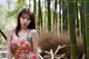 A woman in a colorful dress standing in front of a bamboo forest.