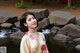 A woman standing in front of a stream in a park.