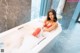 A woman in a red bikini sitting in a bathtub.